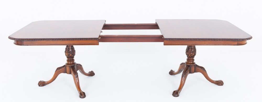 A Regency Revival twin-pedestal mahogany dining table featuring carved edging, turned support pillars, and splayed legs ending in carved feet. View VII