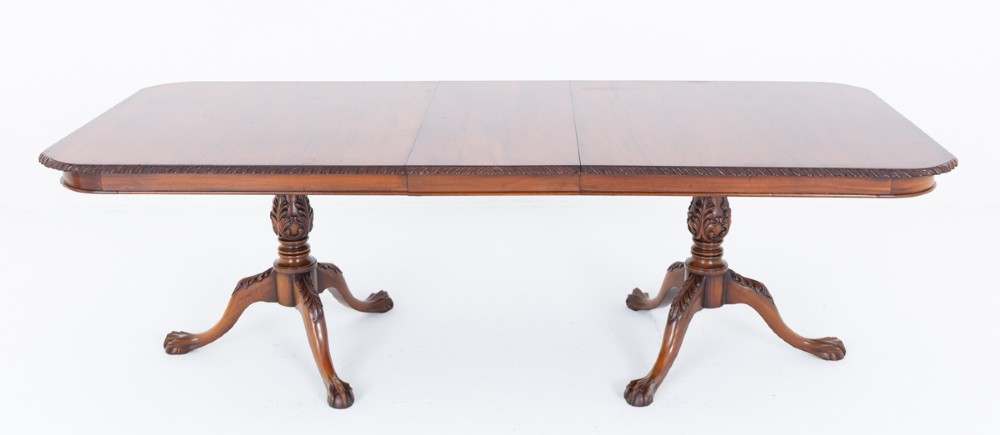 A Regency Revival twin-pedestal mahogany dining table featuring carved edging, turned support pillars, and splayed legs ending in carved feet. View VIII