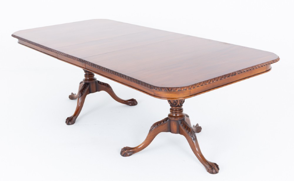 A Regency Revival twin-pedestal mahogany dining table featuring carved edging, turned support pillars, and splayed legs ending in carved feet. View IX