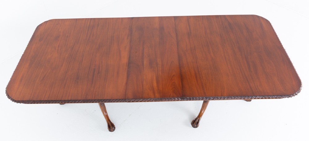 A Regency Revival twin-pedestal mahogany dining table featuring carved edging, turned support pillars, and splayed legs ending in carved feet. View X