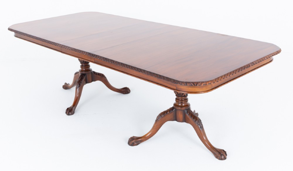 A Regency Revival twin-pedestal mahogany dining table featuring carved edging, turned support pillars, and splayed legs ending in carved feet. View XI