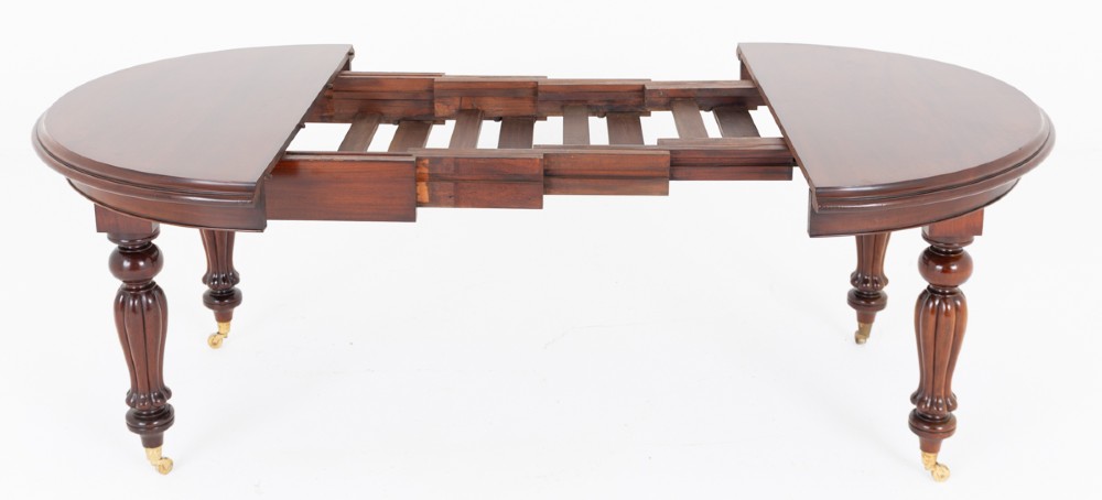 A William IV mahogany extending dining table supported by four reeded turned legs with brass castors. View VI