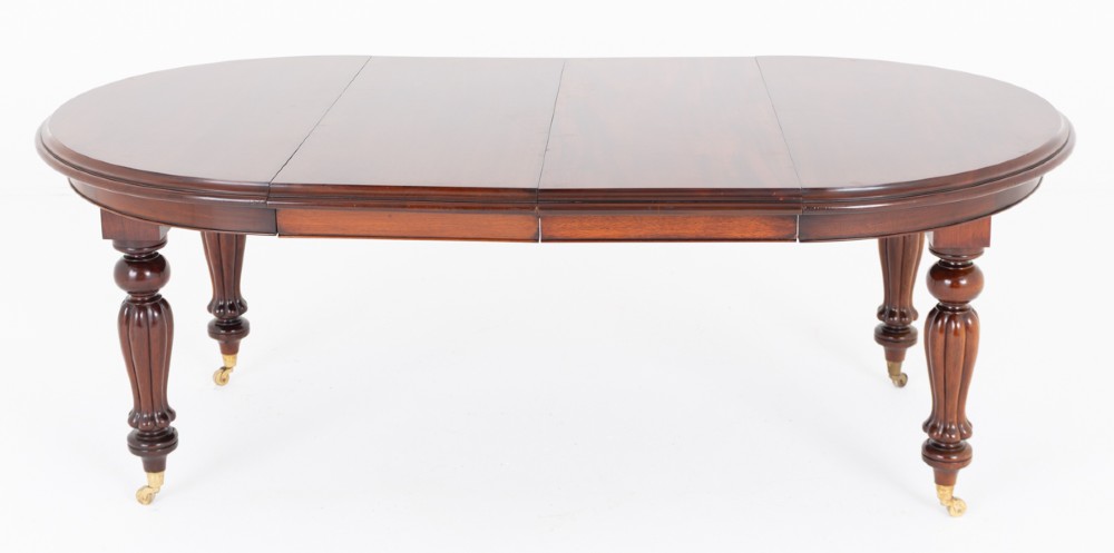 A William IV mahogany extending dining table supported by four reeded turned legs with brass castors. View VII