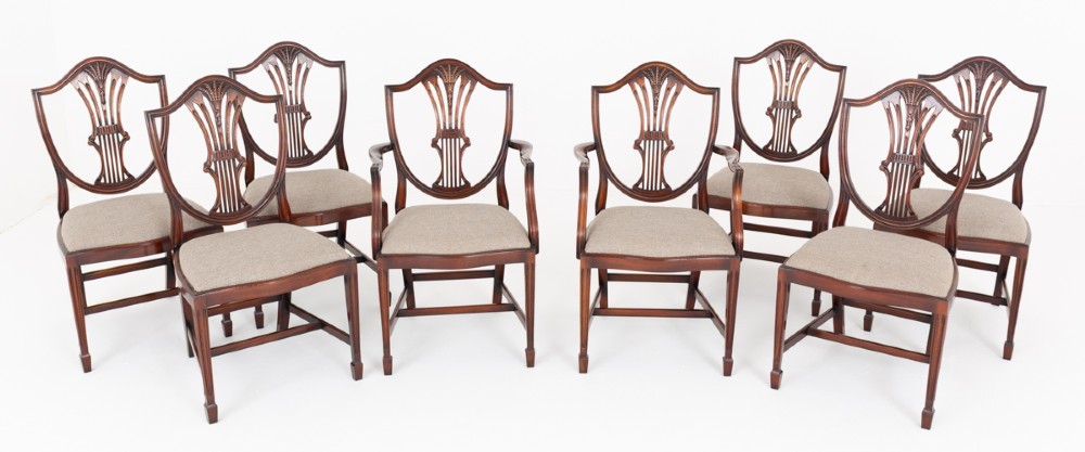 A set of eight mahogany shield back dining chairs comprising six side chairs and two carvers with neutral beige fabric seats.