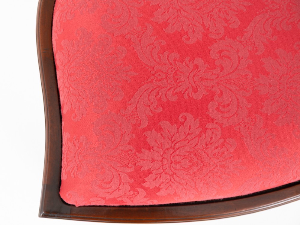 A set of twelve mahogany dining chairs with carved Prince of Wales plume backs and red damask fabric seats arranged in a arc. View VII