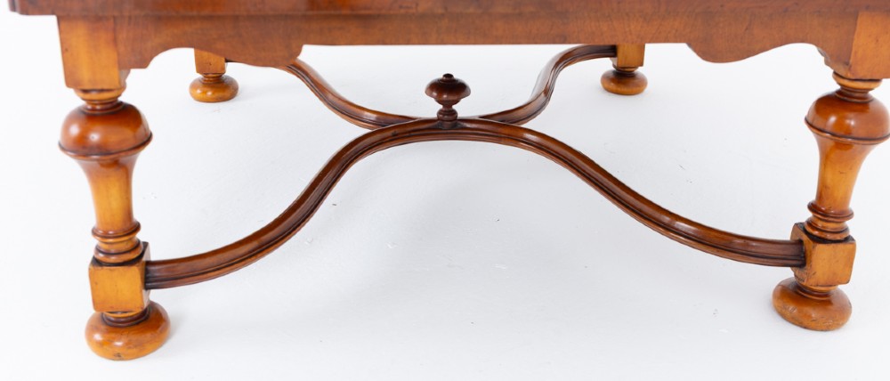 A square low coffee table crafted from warm brown burr walnut veneer with crossbanded borders, turned baluster legs, and curved stretchers. View II