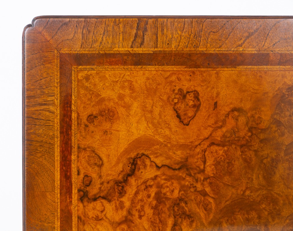 A square low coffee table crafted from warm brown burr walnut veneer with crossbanded borders, turned baluster legs, and curved stretchers. View VI