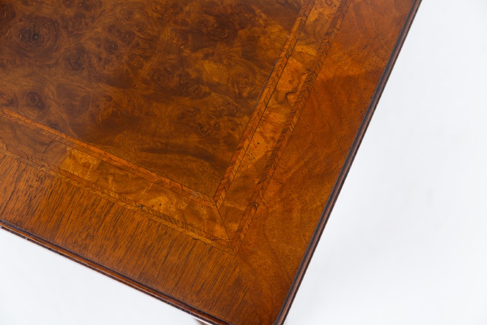 A square walnut coffee table featuring a figured burr walnut top, turned baluster legs, and a curved X-stretcher base. View IV