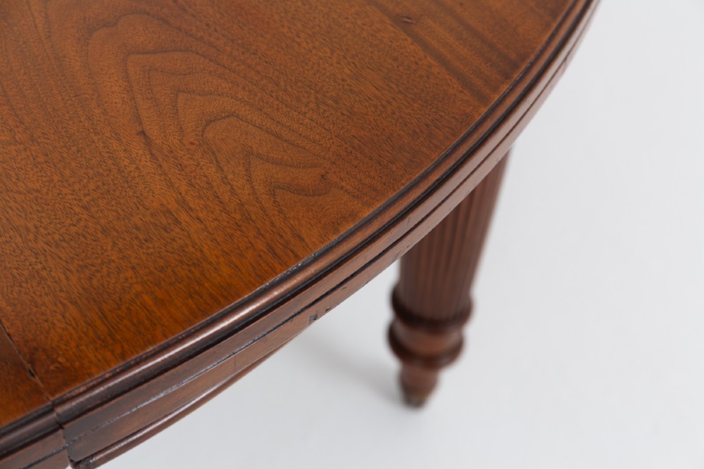 An extended oval walnut dining table with fluted turned legs ending in brass castors. View VIII