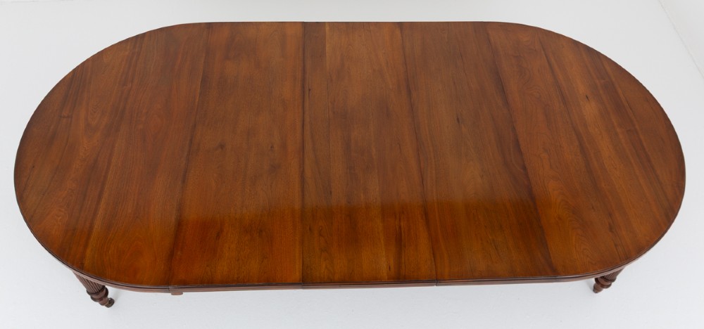 An extended oval walnut dining table with fluted turned legs ending in brass castors. View IX