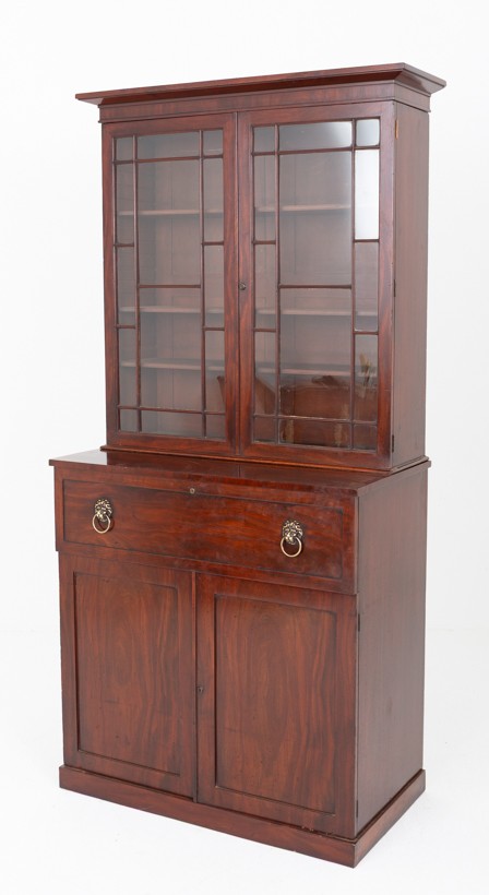 A William IV mahogany secretaire bookcase featuring an upper cabinet with astragal glazed doors, a pull-down secretaire drawer with brass lion mask handles, and a lower two-door cupboard.