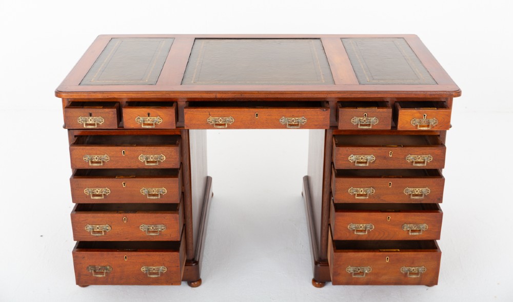 A Victorian mahogany pedestal desk featuring a green leather inset writing surface, multiple drawers with brass handles, and a plinth base. View VI