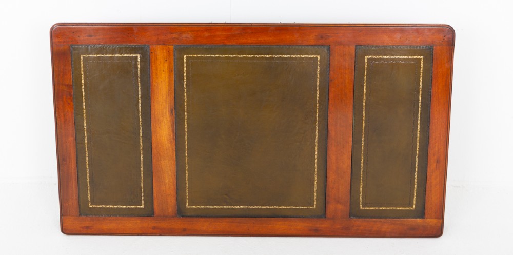 A Victorian mahogany pedestal desk featuring a green leather inset writing surface, multiple drawers with brass handles, and a plinth base. View IX