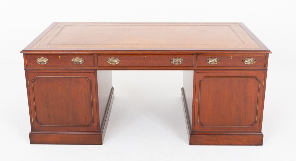 A Georgian style mahogany partners desk featuring a tan leather writing surface, multiple drawers with oval brass handles, and twin pedestal supports. View V