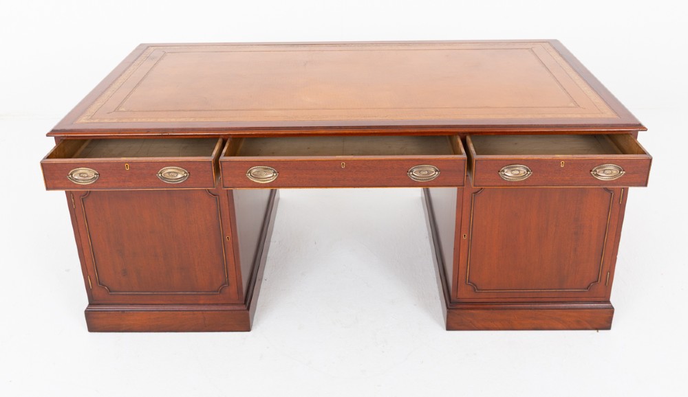 A Georgian style mahogany partners desk featuring a tan leather writing surface, multiple drawers with oval brass handles, and twin pedestal supports. View VI
