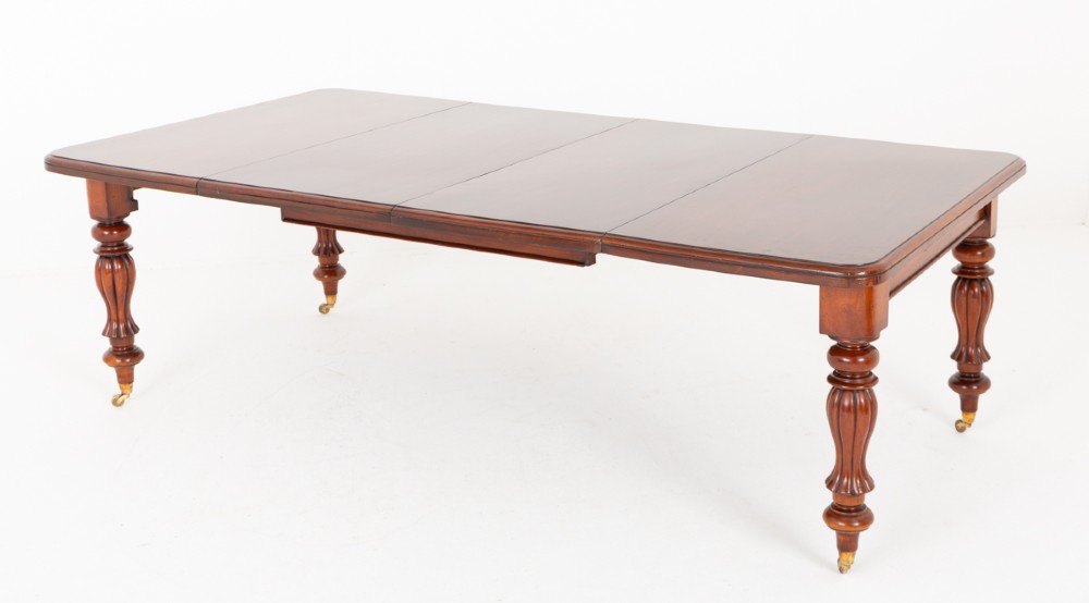 A Victorian mahogany extending dining table with two insertable leaves, fluted turned legs, and brass castors.