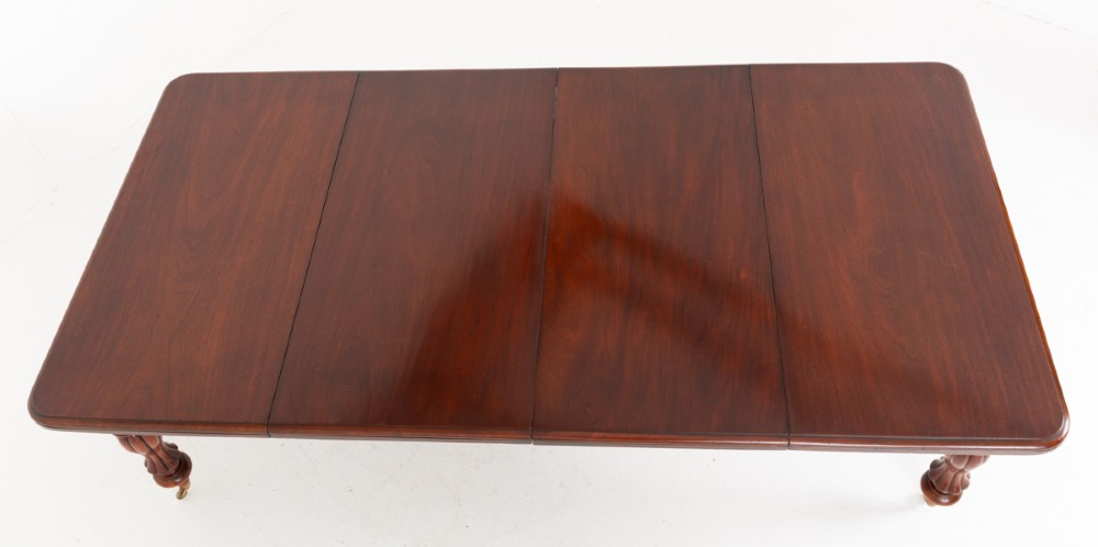 A Victorian mahogany extending dining table with two insertable leaves, fluted turned legs, and brass castors. View XI