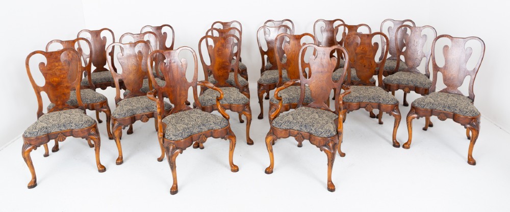 A large set of twenty Queen Anne style elm dining chairs featuring shaped vasiform back splats, upholstered patterned seats, and cabriole legs with carved shell details.