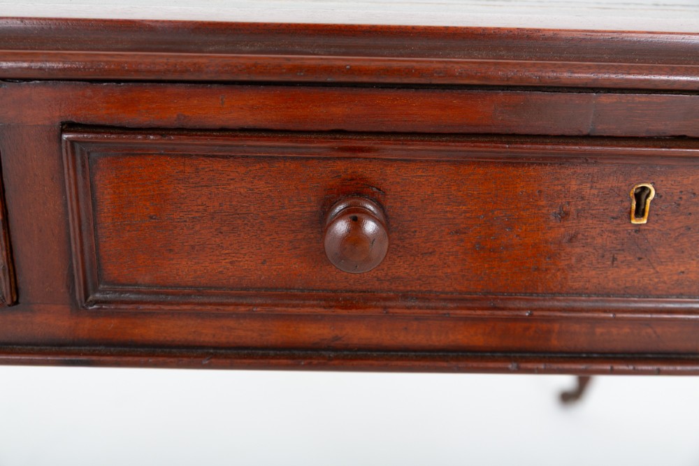 A Victorian mahogany partners writing table featuring a green leather inset top, turned legs on brass castors, and drawers with wooden knob handles. View IV