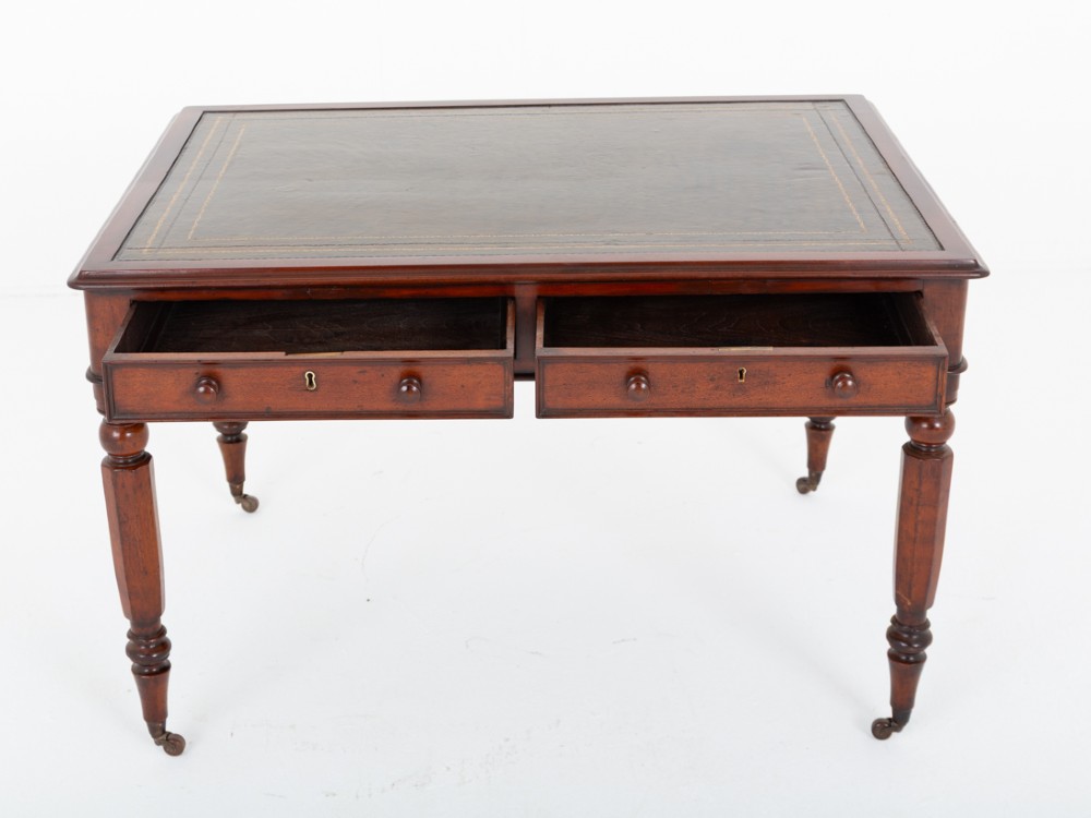 A Victorian mahogany partners writing table featuring a green leather inset top, turned legs on brass castors, and drawers with wooden knob handles. View V