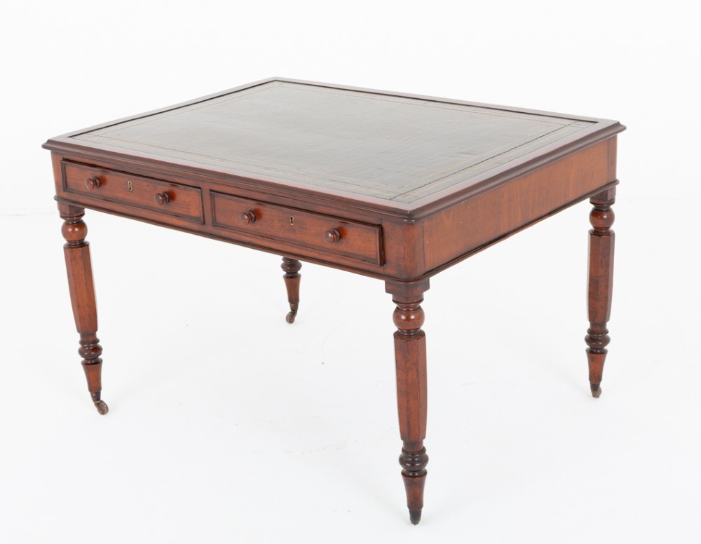 A Victorian mahogany partners writing table featuring a green leather inset top, turned legs on brass castors, and drawers with wooden knob handles.
