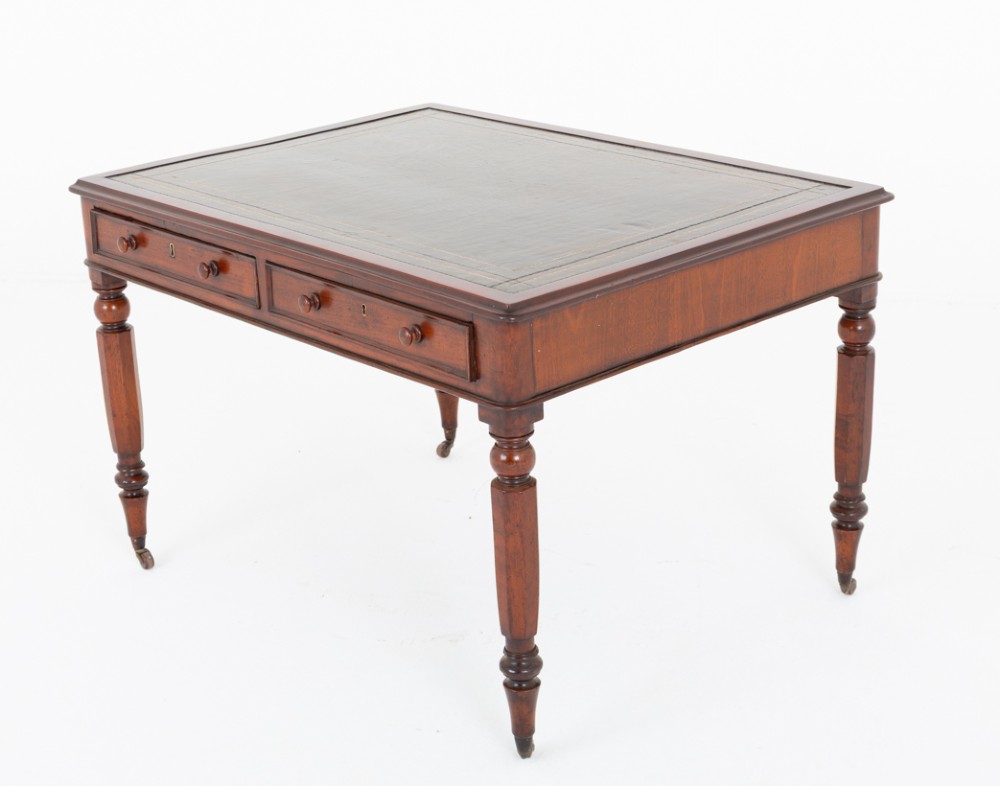 A Victorian mahogany partners writing table featuring a green leather inset top, turned legs on brass castors, and drawers with wooden knob handles. View VI