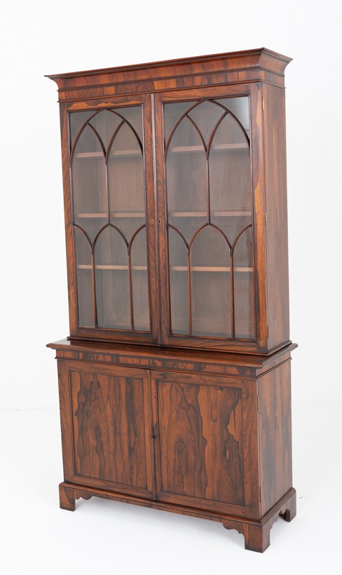 A William IV rosewood glazed bookcase featuring Gothic arched glazing bars on the upper double doors above a two-door solid cabinet base.