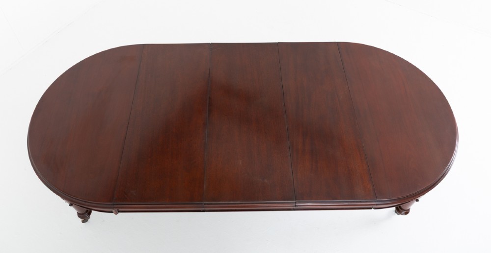 A William IV mahogany extending dining table with turned carved legs and brass castors set against a plain white background. View VIII