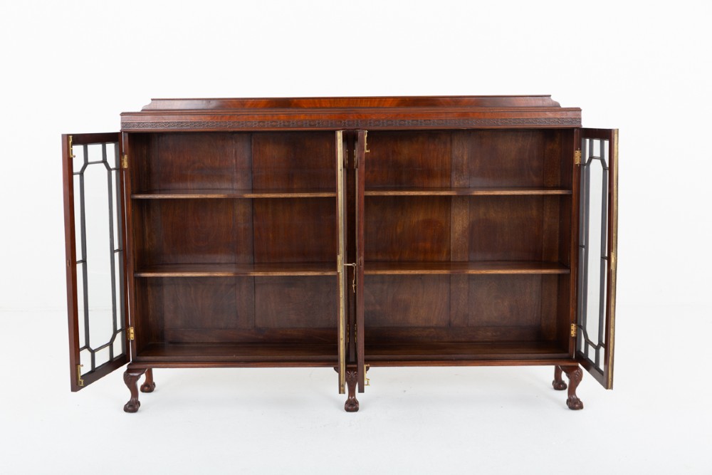 A low mahogany four-door side cabinet featuring geometric astragal glazed glass panels and carved claw and ball feet. View V