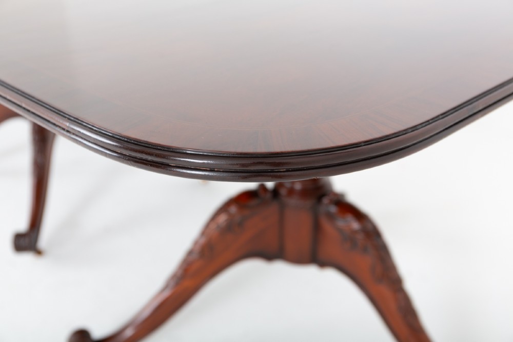 A large Regency style dark mahogany dining table featuring a three-pedestal base with carved splayed legs resting on brass castors. View IV