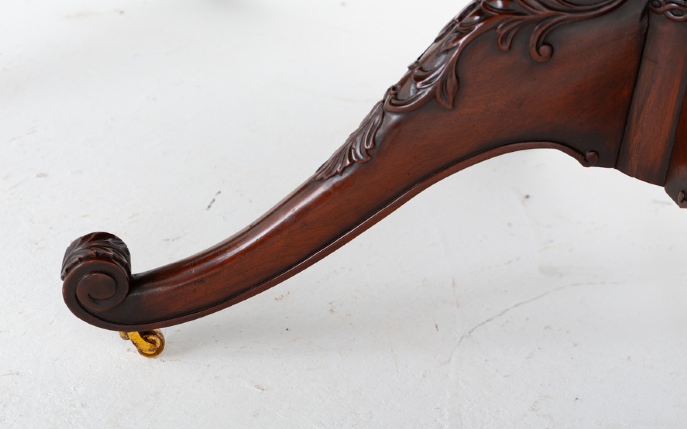 A large Regency style dark mahogany dining table featuring a three-pedestal base with carved splayed legs resting on brass castors. View VIII