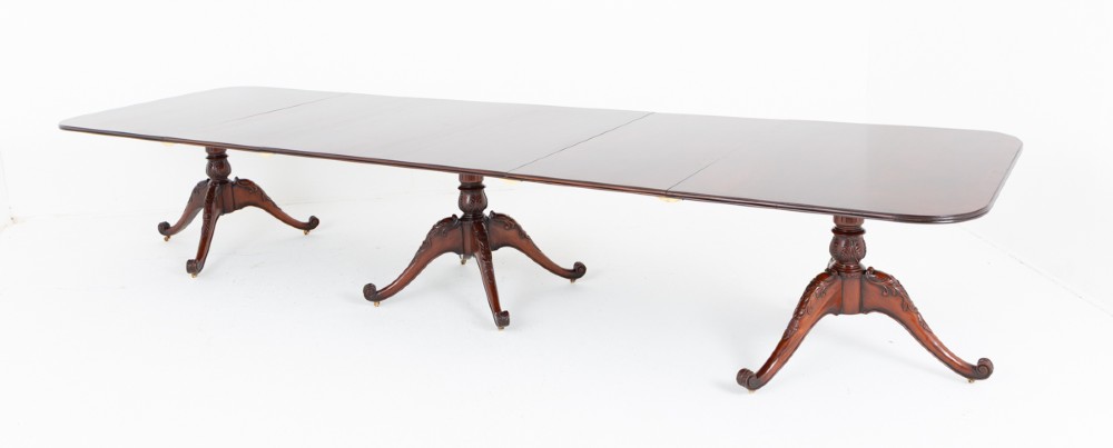 A large Regency style dark mahogany dining table featuring a three-pedestal base with carved splayed legs resting on brass castors. View XII