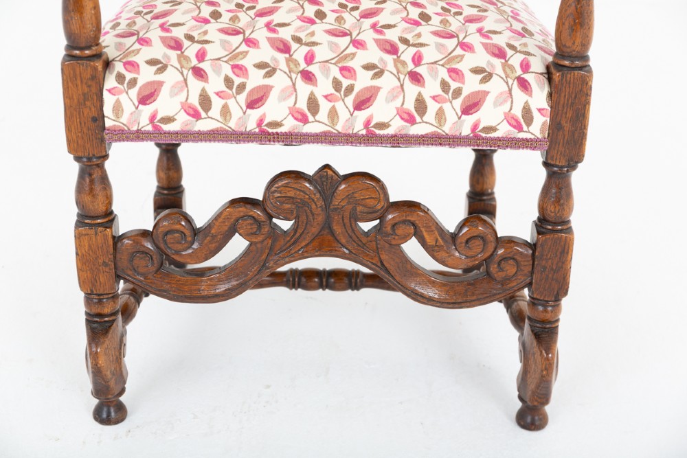 A set of eight Jacobean style oak dining chairs featuring carved scroll stretchers, turned legs, and floral leaf patterned fabric upholstery. View III