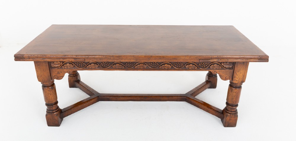 A dark oak Jacobean style extended refectory dining table featuring carved frieze detailing, turned legs, and lower stretchers. View III