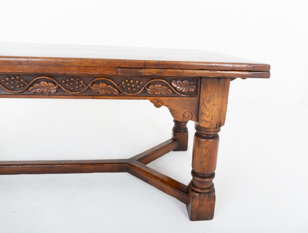 A dark oak Jacobean style extended refectory dining table featuring carved frieze detailing, turned legs, and lower stretchers. View IV