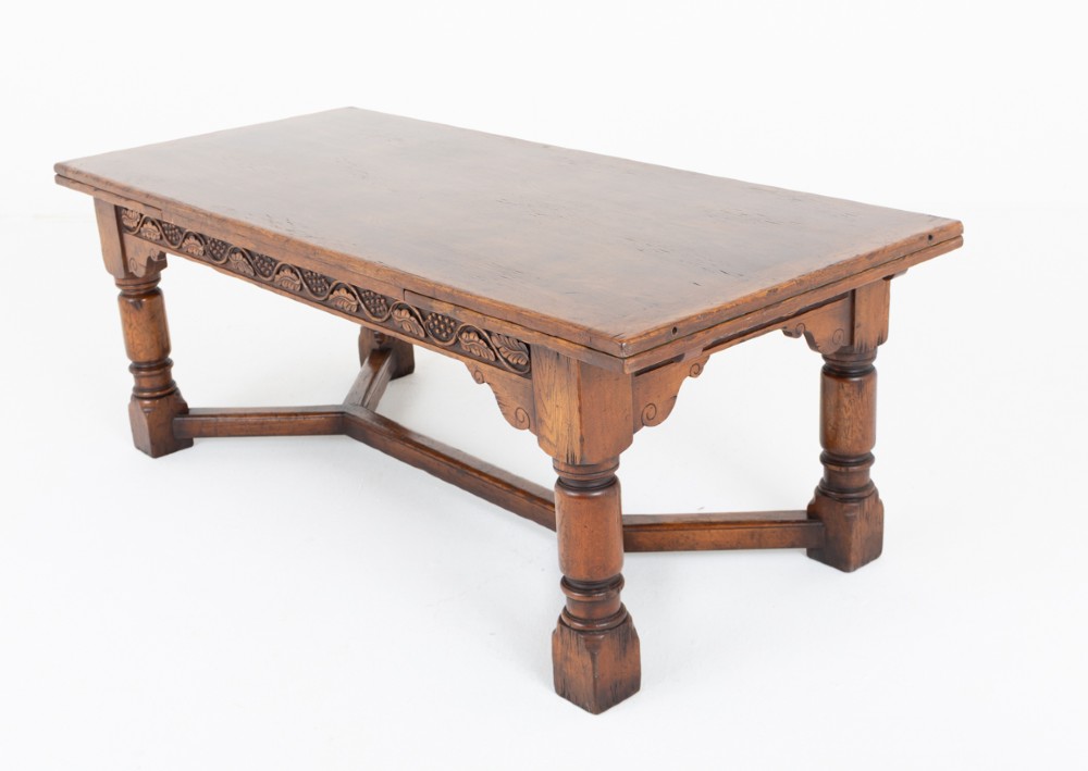 A dark oak Jacobean style extended refectory dining table featuring carved frieze detailing, turned legs, and lower stretchers. View IX