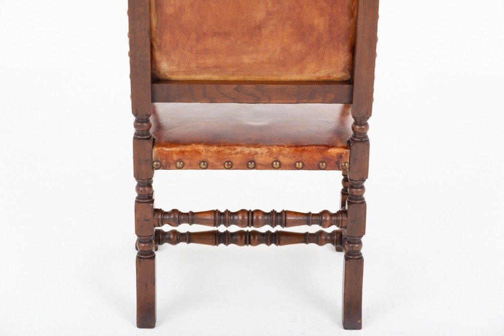 A set of ten brown leather upholstered oak dining chairs with brass studding and turned stretchers, including two carvers and eight side chairs. View XII