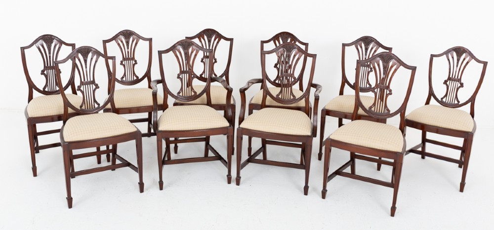 A set of ten mahogany Hepplewhite style dining chairs with shield backs and cream patterned upholstered seats.
