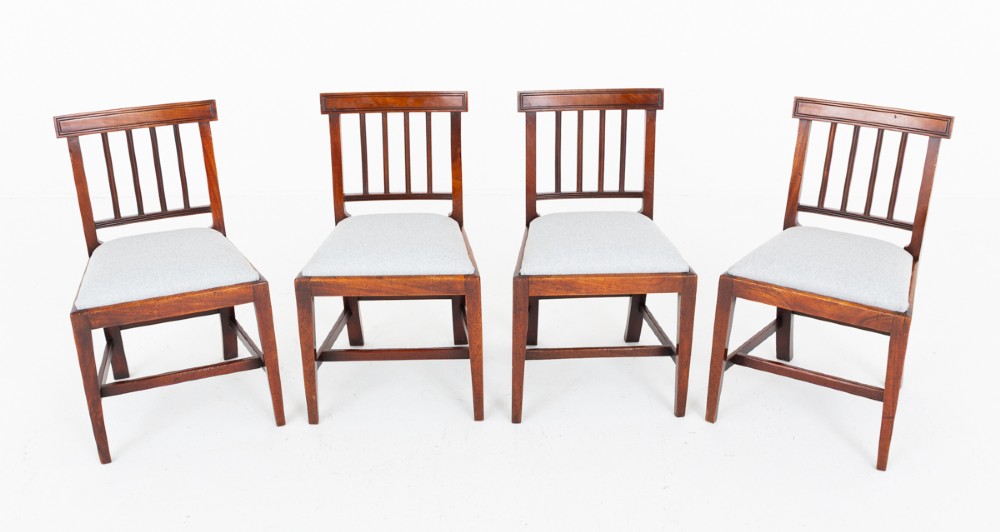 Set of four Georgian mahogany dining chairs with rectangular bar backs, vertical splats, and light grey upholstered seats.