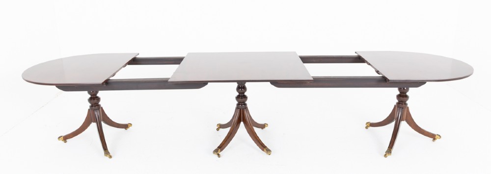 A large Regency Revival dark mahogany three-pedestal dining table with reeded splayed legs and brass claw castors. View VIII
