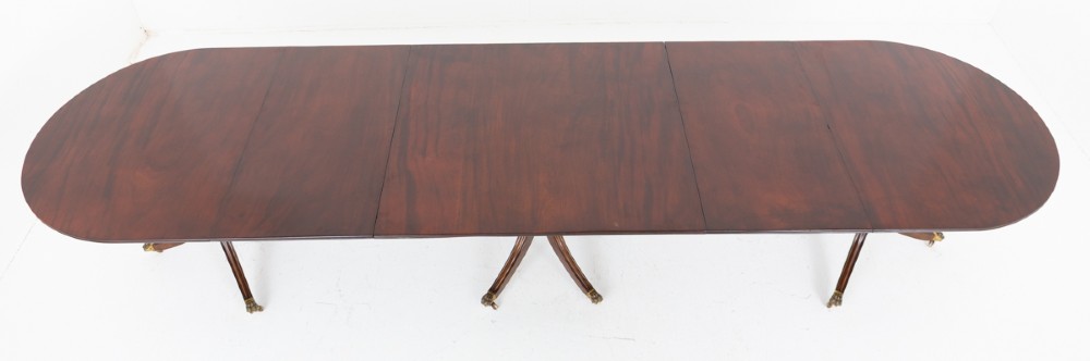 A large Regency Revival dark mahogany three-pedestal dining table with reeded splayed legs and brass claw castors. View X