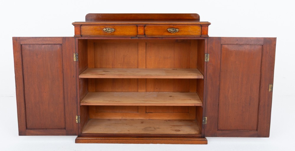 A Victorian mahogany side cabinet featuring two top drawers with brass drop handles above two panelled cupboard doors and a low top gallery. View V