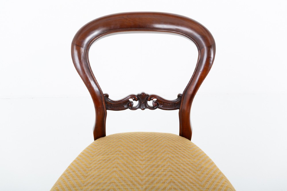 A set of eight Victorian style mahogany dining chairs with rounded balloon backs, carved mid-rails, gold upholstered seats, and fluted front legs. View IV