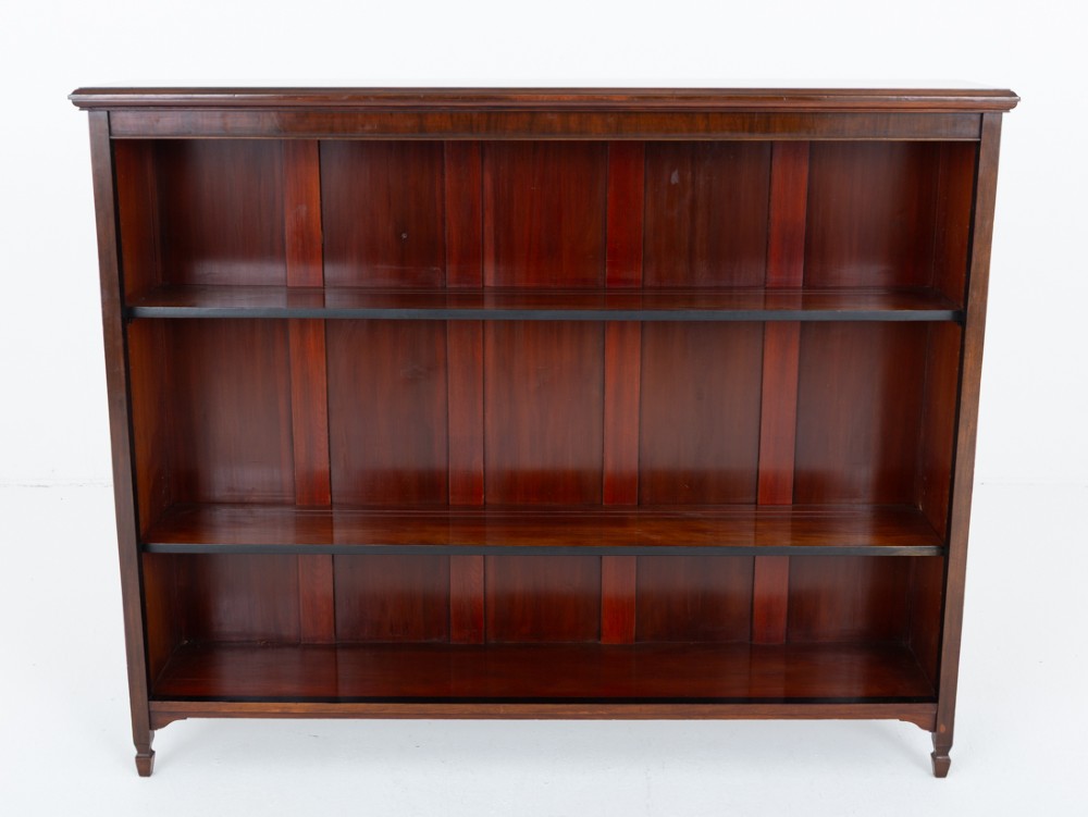 A wide Victorian open mahogany bookcase featuring a panelled back, two horizontal shelves, and turned feet. View II