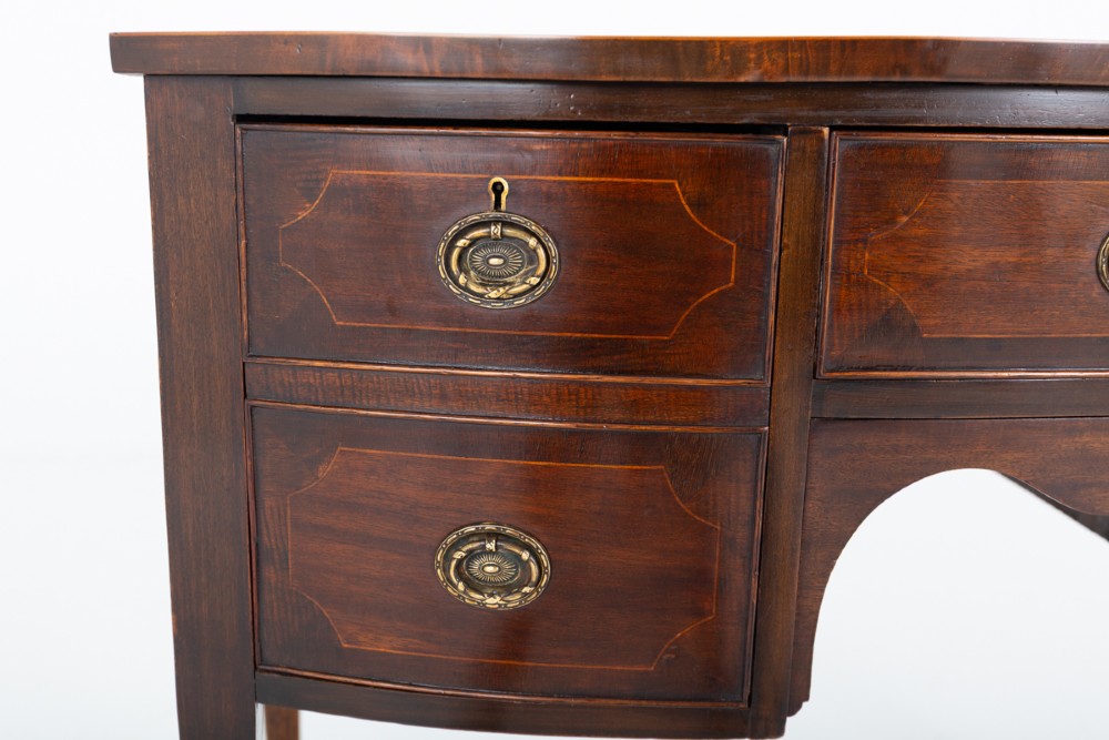 An antique Georgian bow-fronted mahogany sideboard with drawers featuring brass oval drop handles and tapered square legs. View III