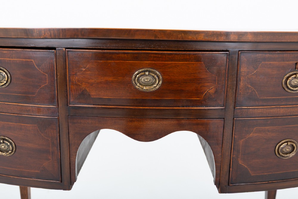 An antique Georgian bow-fronted mahogany sideboard with drawers featuring brass oval drop handles and tapered square legs. View IV