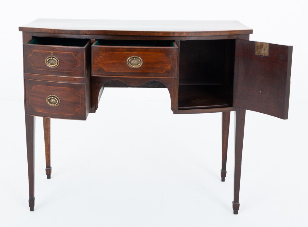 An antique Georgian bow-fronted mahogany sideboard with drawers featuring brass oval drop handles and tapered square legs. View VII