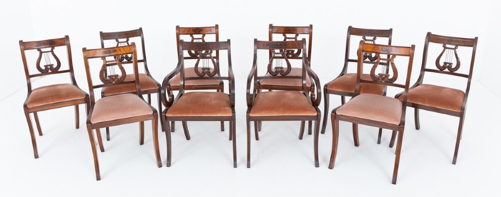 A set of ten mahogany Regency style dining chairs featuring carved lyre back splats, curved armrests on two carvers, and rust-coloured upholstered seats.