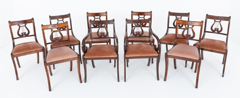 A set of ten mahogany Regency style dining chairs featuring carved lyre back splats, curved armrests on two carvers, and rust-coloured upholstered seats. View II