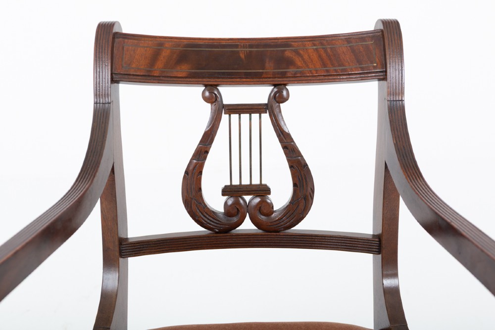 A set of ten mahogany Regency style dining chairs featuring carved lyre back splats, curved armrests on two carvers, and rust-coloured upholstered seats. View IV